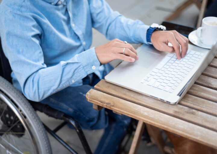 Gros plan sur les mains d’une personne en situation de handicap utilisant le clavier d’un ordinateur portable