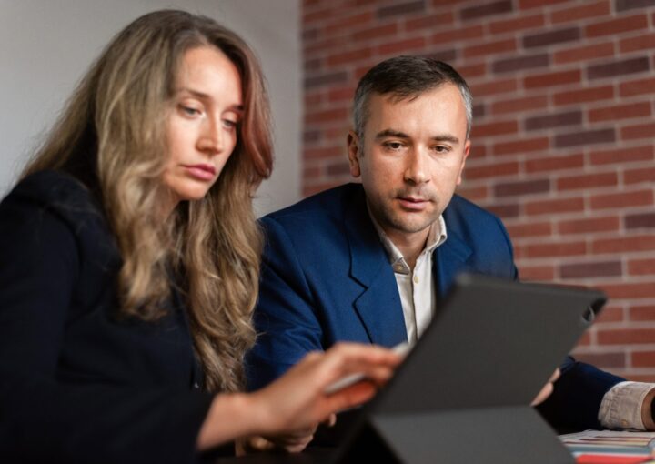 Deux professionnels comparent des offres d'agences SEO autour d'une tablette et de documents au bureau