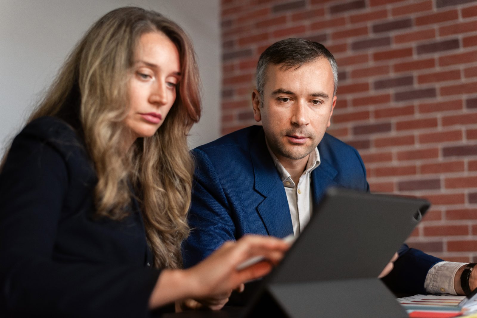 Deux professionnels comparent des offres d'agences SEO autour d'une tablette et de documents au bureau
