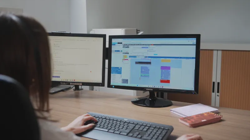 Mains sur un clavier devant deux écrans, les coulisses d'un service
