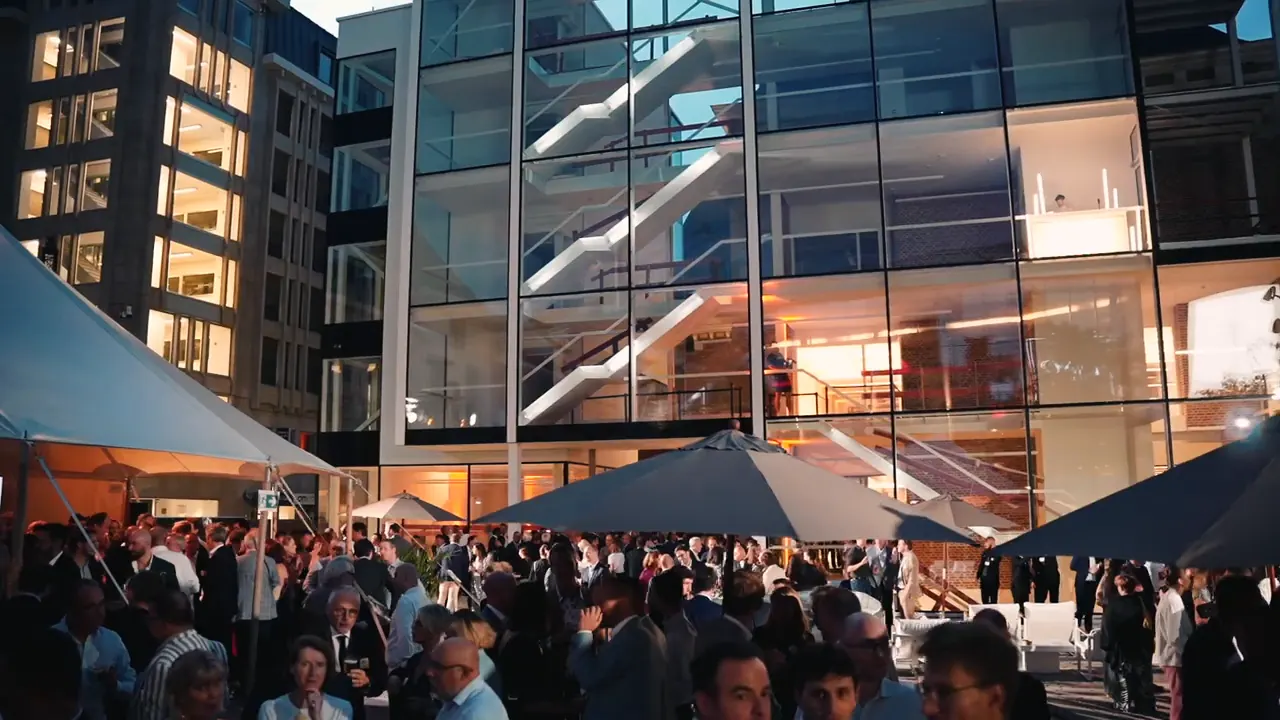 Soirée d'entreprise filmée par AR Digital devant un bùtiment vitré à LiÚge, au crépuscule